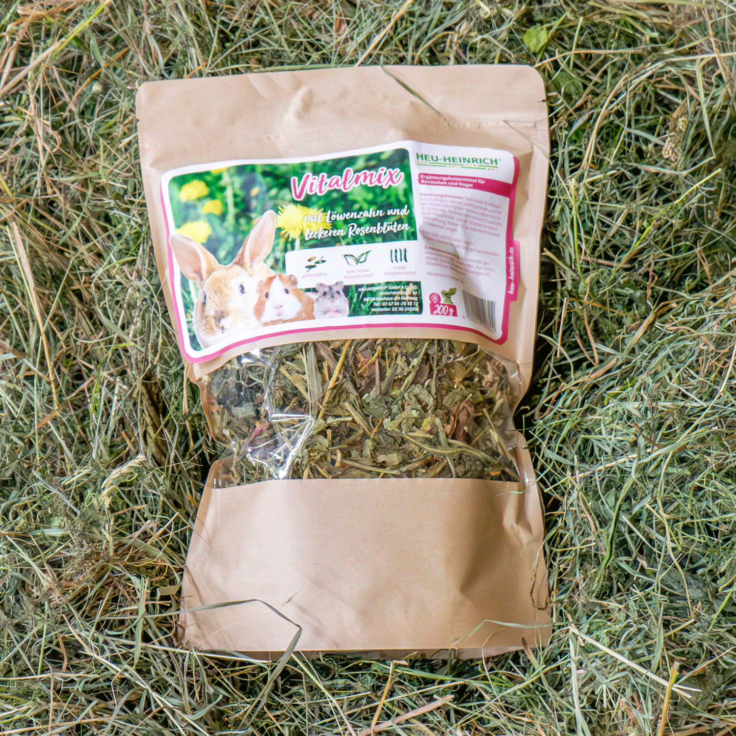 200g Futtermischung " Vital-Mix " von Heu-Heinrich, Trockenfutter für Kaninchen und Nager. Ergänzungsfuttermittel Foto von der braunen Papierverpackung mit Foliensichtfenster. Auf Heu liegend.