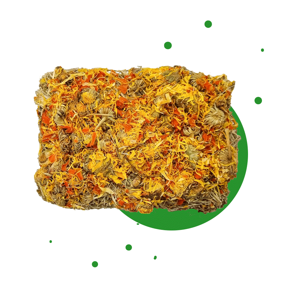 230g Ergänzungsfuttermittel "Heuschnitte" von Heu-Heinrich, Sack/Belohnungsfutter für Nagetiere. Foto von der Heuschnitte. Heu in viereckige Form gepresst und einem Topping mit Ringelblüten und Karotten. Ansicht von oben und mit grünen Punkten im Hintergr